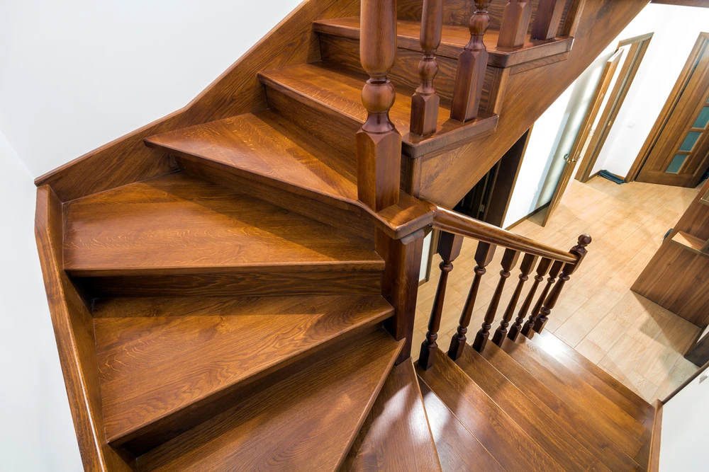Escalier intérieur en bois massif avec rampe tournante et balustres sculptés