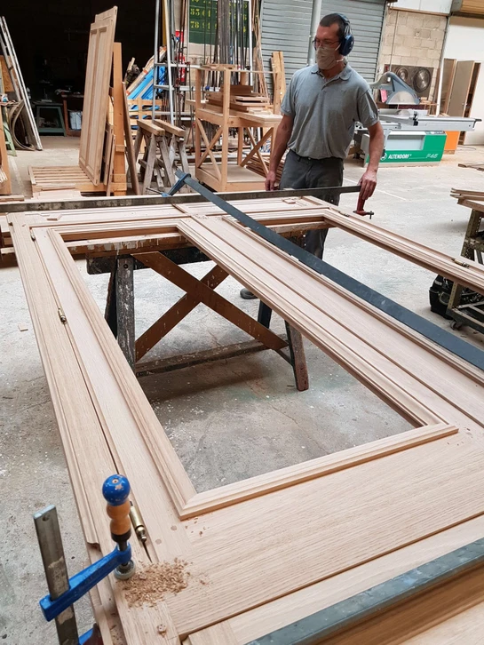 Atelier d'artisan menuisier avec établi en bois ancien, copeaux de rabotage dispersés, outils traditionnels de menuiserie