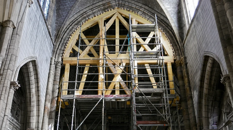 Chantier de construction résidentielle en cours avec charpente bois apparente et échafaudage métallique
