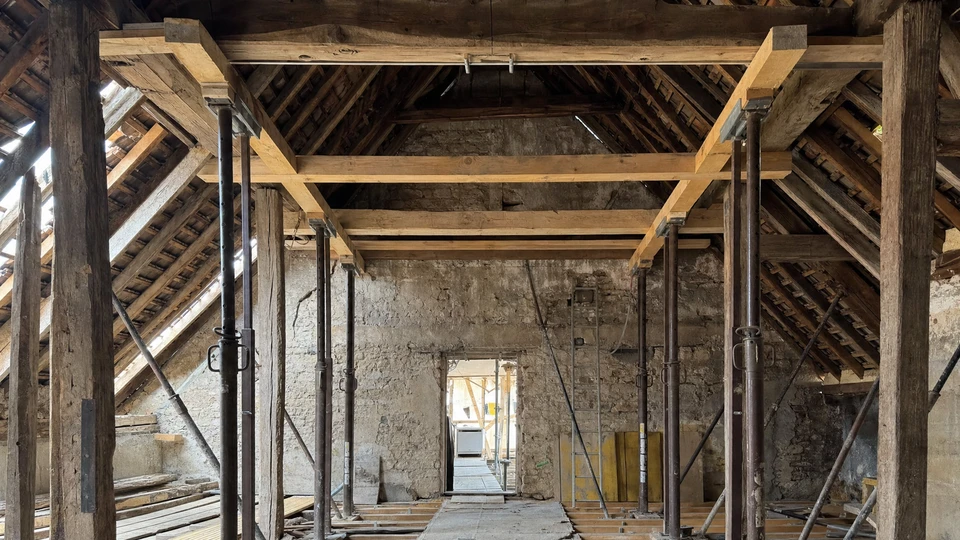 Chantier de construction résidentielle en cours avec charpente bois apparente et échafaudage métallique